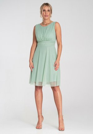 Mintgrünes knielanges Kleid aus leichtem Stoff mit einem taillierten Oberteil, sanften Falten und einem durchsichtigen, geschichteten Rock. Einfaches Ausschnittdesign.