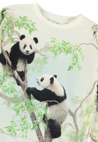 Bijela dukserica s grafikom dviju panda na granama drveća, koja prikazuje izražene crno-bijele uzorke, zelene listove i meku teksturu.
