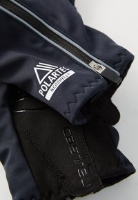 Navy gloves made of Polartec Neoshell fabric with a black textured palm. Features a zipper and embossed branding on the wrist area.