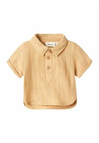 Camicia a maniche corte, a collo, in lino beige chiaro, con tre bottoni rotondi e una finitura testurizzata. Presenta un orlo curvo e un'etichetta sul petto.