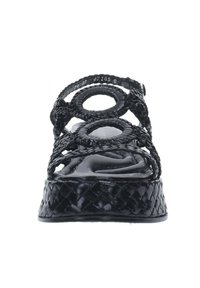 Sandali neri intrecciati con ritagli rotondi, cinturini strutturati e suola interna liscia; piattaforma elevata con una finitura a motivo.