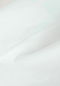 Tissu blanc lisse avec de doux plis et une texture douce, mettant en valeur l'aspect propre et net du matériau.