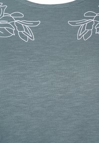 Grått tyg med ett vitt minimalistiskt bladomrissdesign nära halsringningen på båda översidorna.