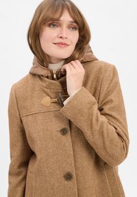 Brauner Fischgrätenmantel mit Kapuze, ausgestattet mit einem leichten braunen Futter, hölzernen Knebelverschlüssen und zwei Knöpfen vorne. Texturierter Stoff.