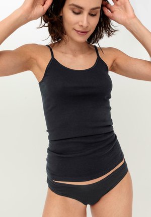 Schwarzes Baumwolltanktop mit dünnen Trägern, figurbetontem Design und dehnbarem Material, kombiniert mit passenden, tief sitzenden Unterhosen, beide in einer einheitlichen dunklen Farbe.