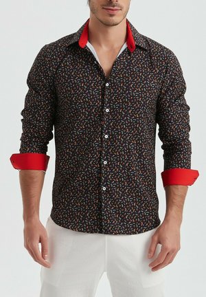 Chemise noire à boutons avec un motif paisley coloré ; col et poignets rouges ; manches longues, design ajusté et texture lisse.