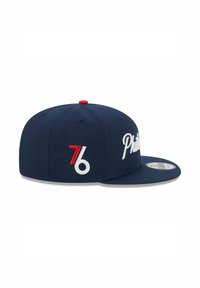 Casquette de baseball bleu marine avec inscription blanche "Phillies" et un bouton accentué en rouge. Comprend un logo "76" blanc et rouge sur le côté.