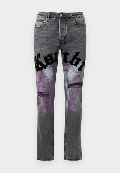 Μαύρα ξεθωριασμένα τζιν με μοτίβο μωβ αγγελικών φτερών στους μηρούς και μεγάλο μαύρο γοτθικό κείμενο κατά μήκος του άνω μέρους των ποδιών, με δύο φθαρμένα σκισίματα.