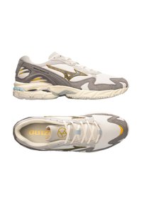Sneakers atletici bianchi e grigi con una tomaia in mesh, accenti grigi testurizzati, logo giallo e un design della suola unico e ondulato.