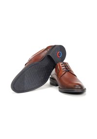 Zapatos de vestir de cuero marrón con un upper texturizado, cordones negros y una suela de goma estampada con un detalle de acento de color.