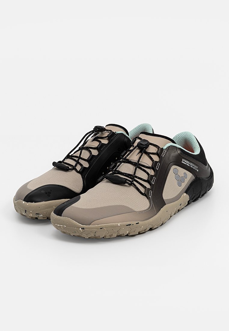 Zapatillas deportivas ligeras en color beige con acentos en negro, fabricadas con tejido texturizado y suelas de goma. Cuentan con un diseño sin cordones y un collar acolchado.