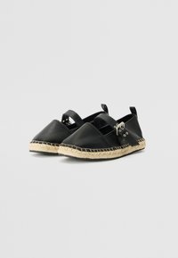 Zwarte leren espadrilles met een ronde neus, bandjesdetail en jute touwzool. Voorzien van zilverkleurige hardware-accenten.