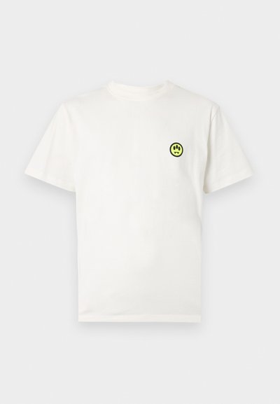 Weißes Baumwoll-T-Shirt mit kurzen Ärmeln, das ein kleines schwarzes und neongrünes rundes grafisches Design auf der Brust zeigt, das ein Smiley-Gesicht darstellt.