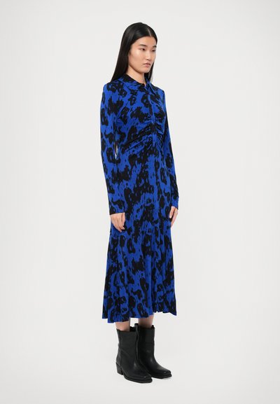 Haljina dugih rukava s plavim i crnim animal printom, detaljem nabora sprijeda i lepršavim krojem, uparena s crnim gležnjačama.