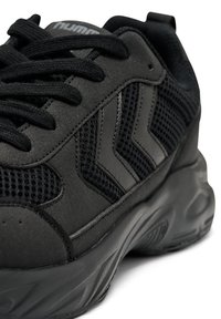 Czarne sportowe buty z panelami z siateczki i zamszu, grubą podeszwą, czarnymi sznurowadłami oraz bocznymi akcentami w kształcie jodełki.