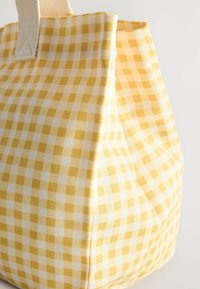 Sac en tissu à motif vichy jaune et blanc avec poignées beiges, présenté en gros plan de côté sur fond blanc.