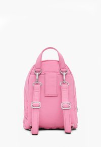 Mały różowy plecak z regulowanymi szelkami i uchwytem do noszenia na górze na białym tle.