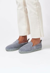 Grå mocka slip-on skor med en vävd jute-mellansula och en ljusgrön yttersula, med en utskärning design på sidorna och en liten hälflik.