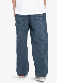 Blå denim cargo bukser med en afslappet pasform, der har flere lommer, en falmet tekstur og en tapered benstil. Detalje med elastisk talje.