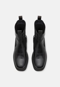 Sorte lær ankle boots med en glat overflade, elastiske sidepaneler, trækstropper og en flad gummisål. Klassisk Chelsea boot design.
