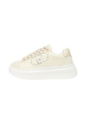 Sneaker beige a bassa altezza con suola bianca spessa, design con lacci e decorazioni in pietre preziose che formano un motivo geometrico sul lato.