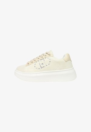 Sneaker beige a bassa altezza con suola bianca spessa, design con lacci e decorazioni in pietre preziose che formano un motivo geometrico sul lato.