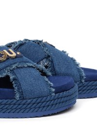 Sandali con platform in denim con incroci a frangia e dettagli in metallo dorato. Caratterizzati da una suola spessa in juta intrecciata di colore blu scuro.