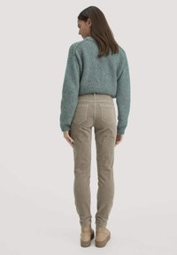 Lichtblauwe gebreide trui en beige corduroy broek met achterzakken, gecombineerd met tan platformlaarzen. De outfit is van achteraf gezien.