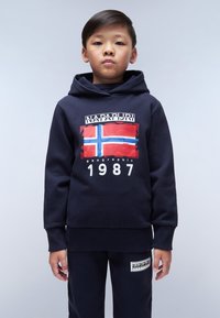 Sudadera navy con un gráfico frontal que presenta la bandera noruega, el texto "NAPAPIJRI" y el año "1987". Acompañada de pantalones navy a juego.