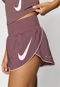 Σορτς Nike σε απόχρωση μάβρου. Διαθέτει ψηλή ζώνη μέσης και στρωματοποιημένο σχέδιο με λευκό λογότυπο Swoosh. Λείο υλικό και αντίθετη επένδυση.