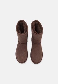 Bruine suede enkellaarzen met een zachte binnenvoering, een gladde buitenkant en een ronde neus. Heeft minimale stiksels en geen zichtbare hardware.