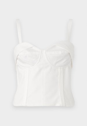 Valkoinen lyhyt bralette, jossa on säädettävät hihnat, pehmeä kangas, muotoiltu vartalo-osa, kaareva pääntie ja sivusaumat määrittelyä varten.