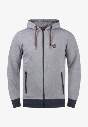 Siva zip-up hoodie od teksturirane tkanine, s kapuljačom, dvostrukim bočnim džepovima, crnim akcentima i uzorkovanim vezicama. Okrogli logo na prsima.