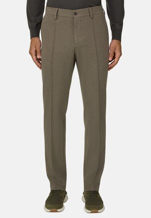 Pantalon marron coupe droite porté avec des baskets vert foncé et un haut noir à manches longues, montré de la taille aux pieds.