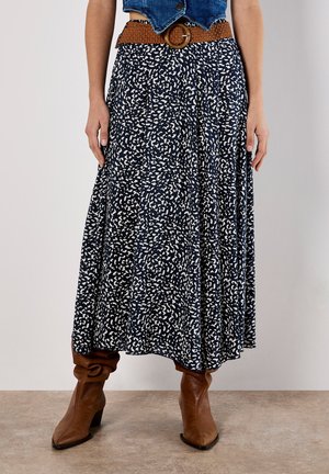 Flared, ankle-length skirt in navy blue with white abstract pattern, made from lightweight fabric, paired with a woven brown belt and brown boots.
