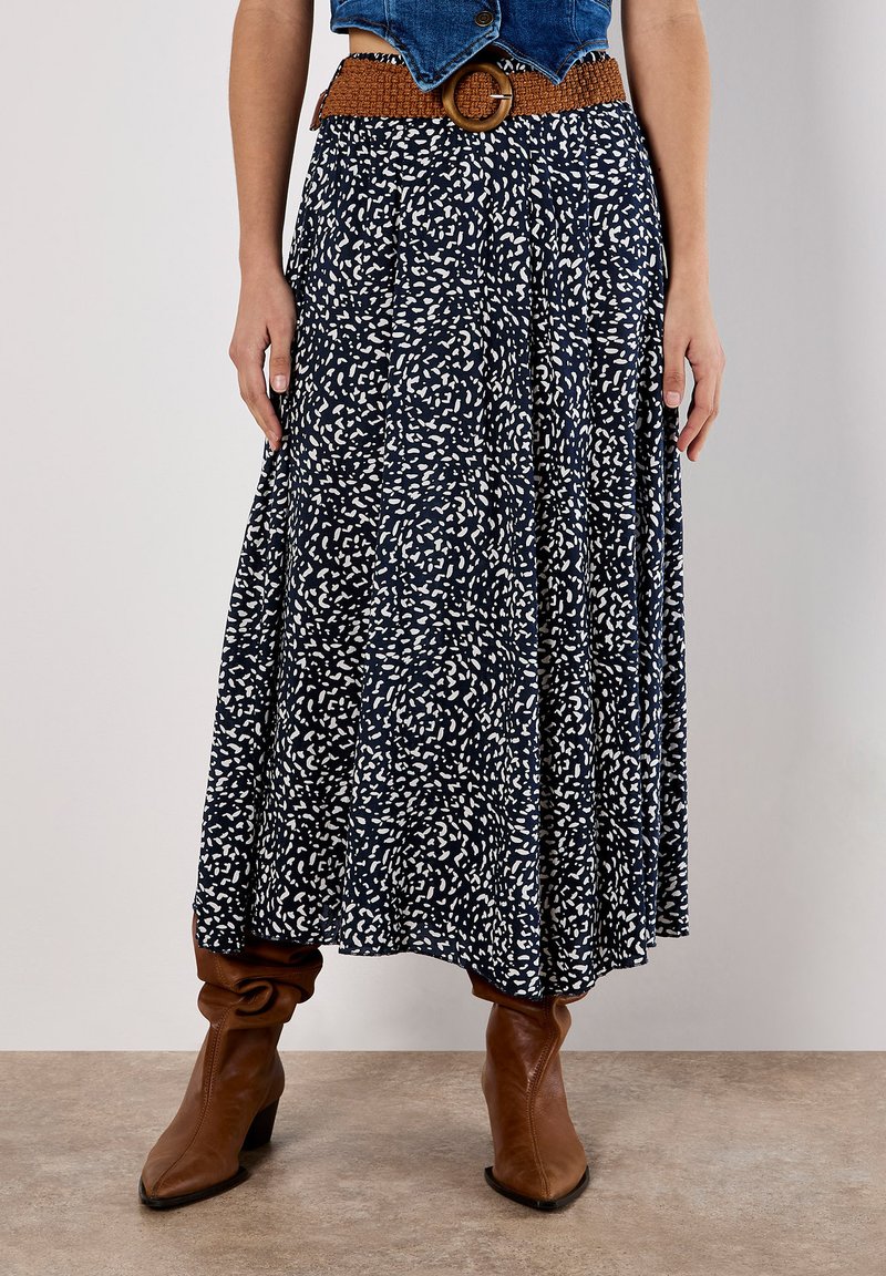 Flared, ankle-length skirt in navy blue with white abstract pattern, made from lightweight fabric, paired with a woven brown belt and brown boots.
