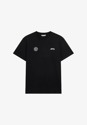 Czarna bawełniana koszulka z okrągłym dekoltem, z białym haftowanym napisem "UNFAIR" i okrągłym logo na lewej piersi.