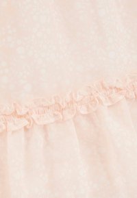 Robe rose clair ornée d'un motif floral, en tissu transparent, avec un ourlet froncé. La texture douce met en valeur l'apparence délicate de la robe.