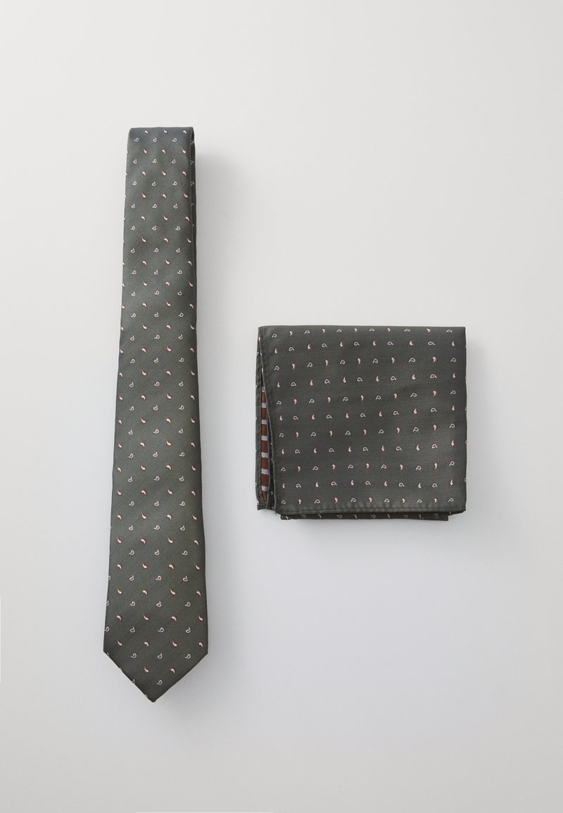 Cravate en soie verte avec un motif blanc et rose, accompagnée d'un mouchoir coordonné affichant le même design. Les deux ont une texture lisse.