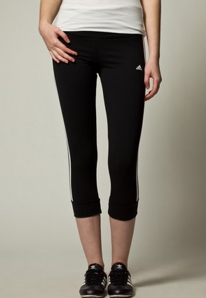 Leggings sportivi neri con strisce bianche ai lati e orli a costine, realizzati in tessuto elasticizzato. Logo Adidas vicino alla vita.