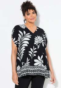 Schwarze Bluse mit weißem Blumenmuster, V-Ausschnitt, kurzen Ärmeln und kontrastierendem Bordüren-Detail am Saum. Leichtes, lässiges Design.