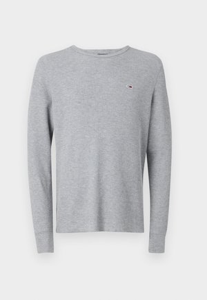 Sweatshirt cinza de manga longa com gola redonda e um pequeno logótipo no peito. Apresenta um tecido texturado e punhos ajustados.