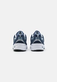 Zapatillas deportivas azul marino con parte superior de malla, acentos blancos y una suela acolchada. Presentan un patrón texturizado en el talón y detalles reflectantes.