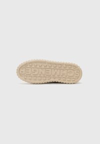 Semelle en caoutchouc crème avec une texture antidérapante, présentant un nom de marque en relief et des motifs d'étoiles sur la surface, design à bout rond.