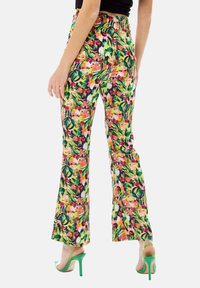Flared trousers in a vibrant floral pattern featuring pink, yellow, and green hues. Made from lightweight fabric with a smooth texture.