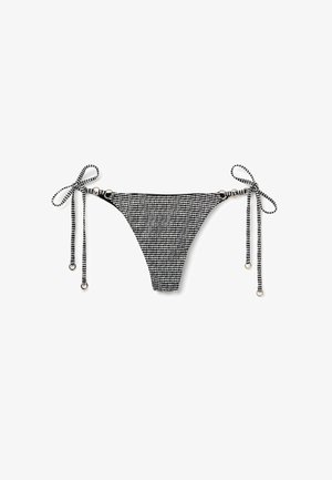 Parte inferior de bikini a rayas en blanco y negro con lazos ajustables, que presenta detalles de metal y un diseño de tela texturizada.