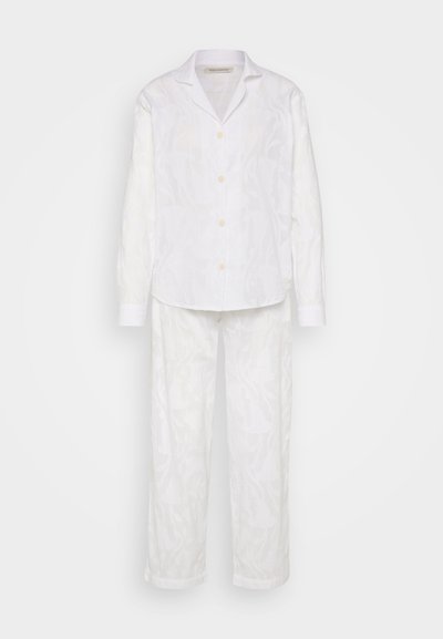 Biele ľanové pyžamo pozostávajúce z košele na gomb�íky s dlhými rukávmi a nohavíc. Obe časti majú jemný tónový vzor a voľný strih.