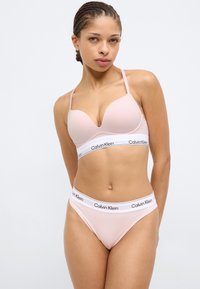 Σετ ροζ σουτιέν και εσώρουχο με ομαλή υφή. Το σουτιέν έχει λεπτές ρυθμιζόμενες τιράντες και ταινία με το λογότυπο Calvin Klein.