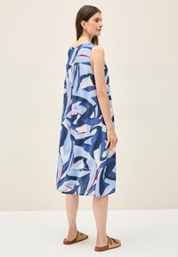 Vestido sin mangas en azul con patrones abstractos en marino, blanco y rojo; corte holgado, hasta la rodilla y hecho de tejido ligero.