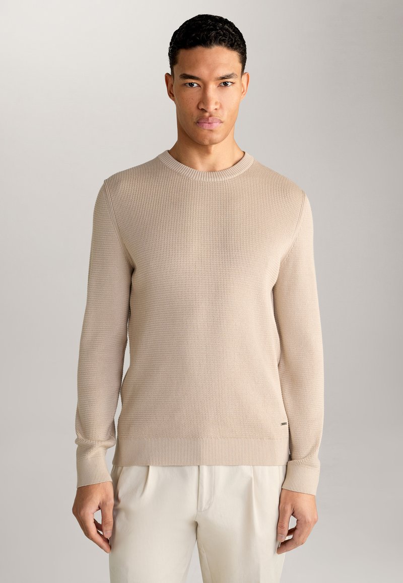 Maglione beige in maglia con scollatura rotonda e maniche e orlo a coste. Presenta una superficie testurizzata e un logo discreto sul lato.